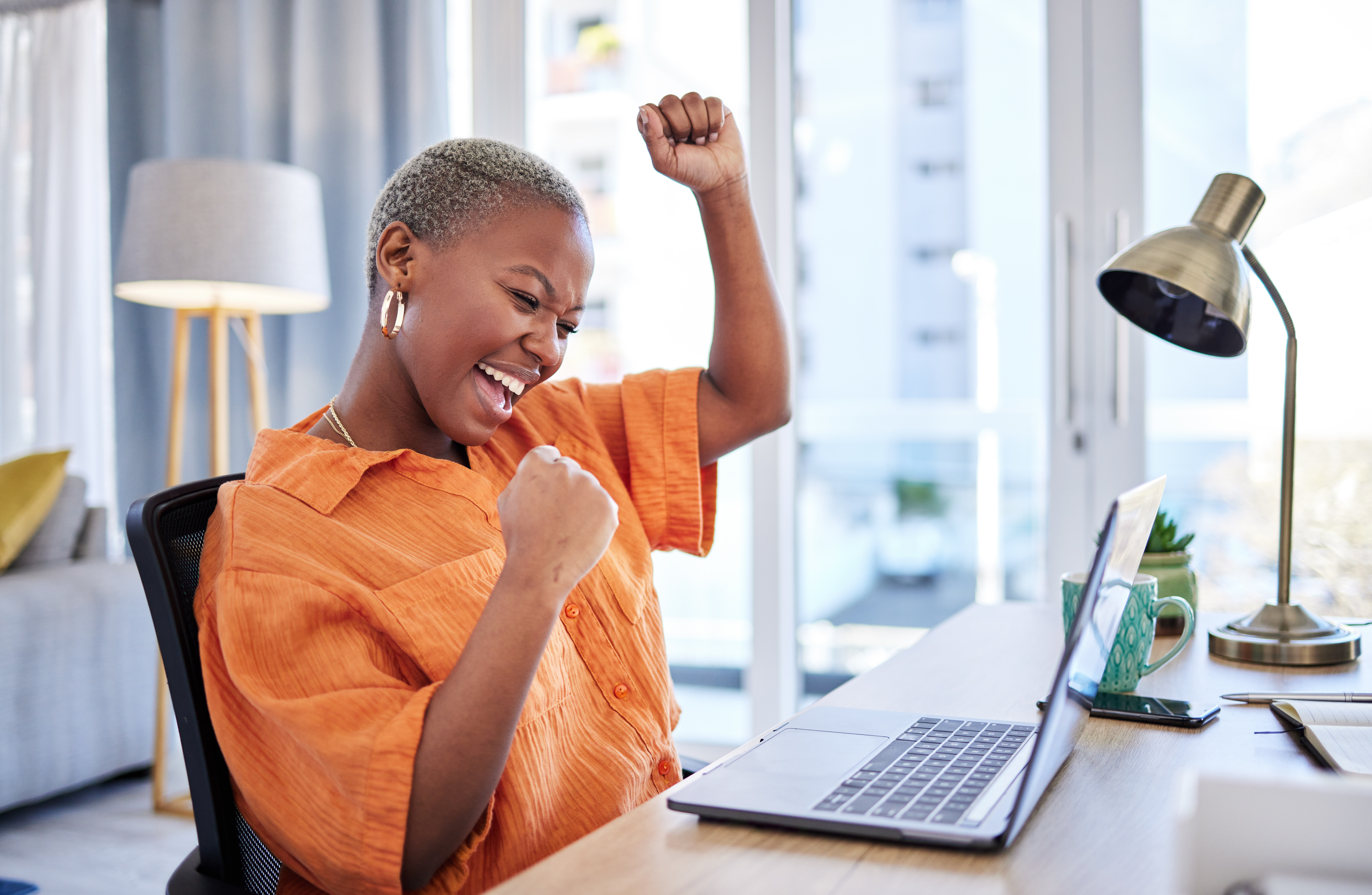 Businesswoman, laptop or winner with fist pump for winning, success or promotion bonus in home office. Happy black woman trader trading or cheering with prize, goal target or good news in remote work.